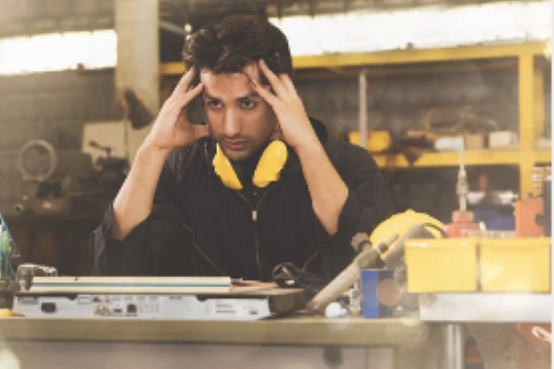 stressed out man working at a desk in a manufacturing facility